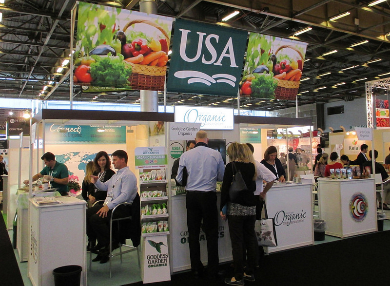 A small crowd of people congregate at a booth in a food and beverage trade show