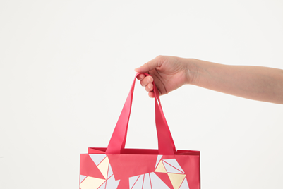 A person holds a pink canvas tote against a white background