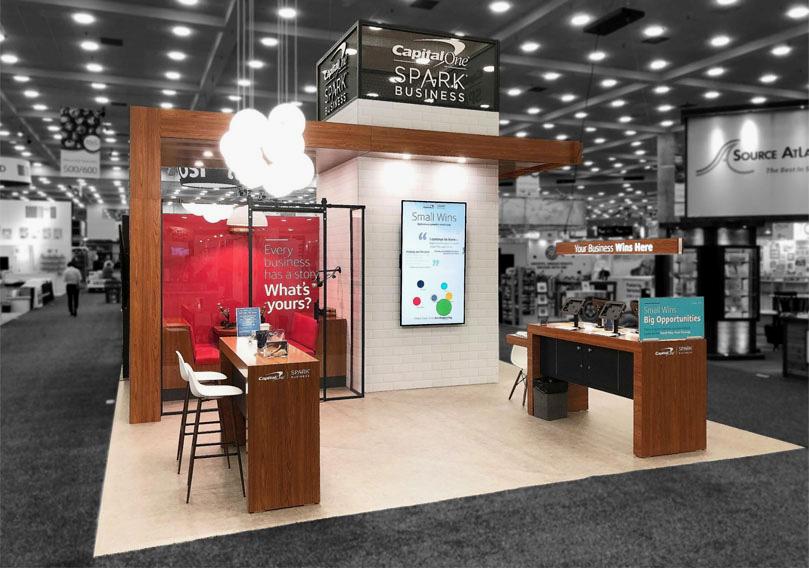 An example of a clean and tidy booth with enough space for staff and guests, tall chairs, and storage space to help staff maintain good trade show etiquette.