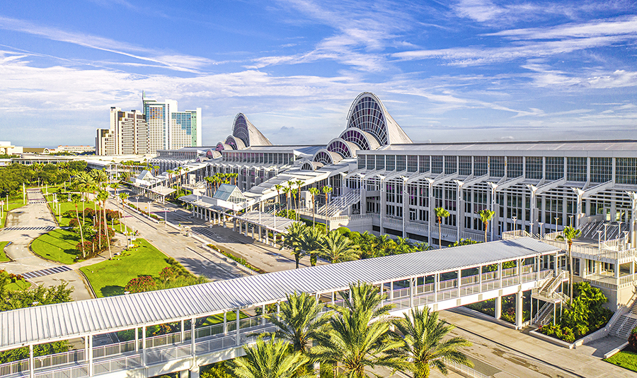 The sweeping curves and white-framed window walls of the Orange County Convention Center soar up against a sunny sky in Orlando.
