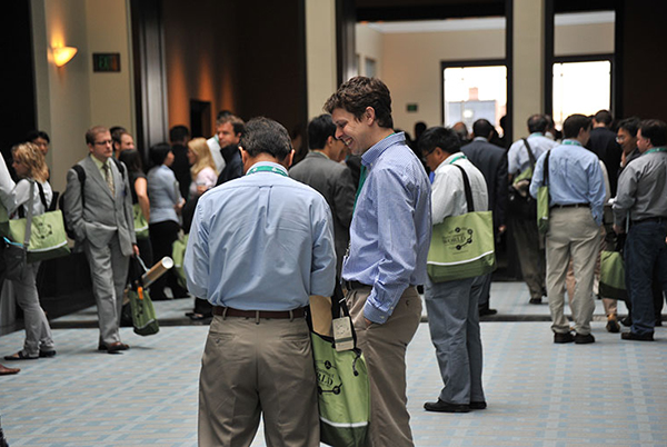 Nanotech conference attendees carrying matching tote bags chat and mill in the conference center hallways.