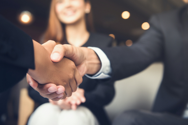 An exhibitor and a guest shaking hands after talking. This demonstrates the kind of engagement you can reward with a promotional item if you're planning your trade show booth on a budget.