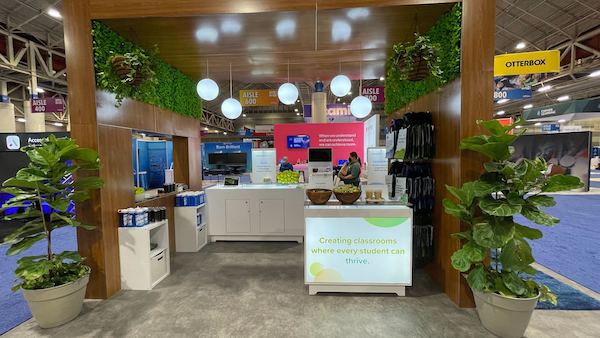 A booth created by Cardinal around the theme of thriving with lots of green plants, demonstrating how to work a trade show with a booth that stands out