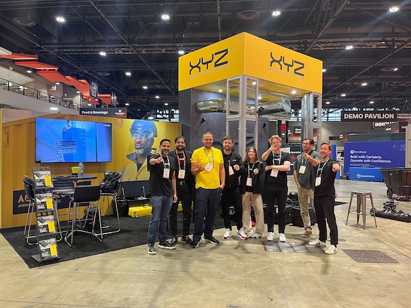 The XYZ team at their booth, with the lead wearing yellow and all other staff wearing black. This reflects their brand colors and one of our top trade show attire ideas and tips.