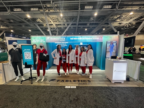 Booth staff wearing scrubs and doctor's coats at a medical show. Because they sell scrubs, it's a great trade show attire idea to match how the industry dresses.