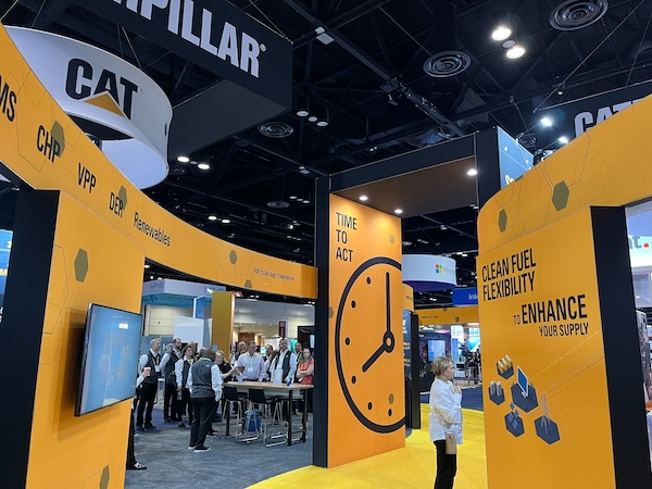 A person exploring the interactive Caterpillar booth at DISTRIBUTECH Show, featuring curved walls, engaging graphics, and video content