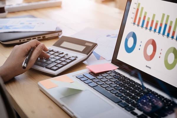 Business person uses a calculator and our trade show budget template to calculate company expenses and performance