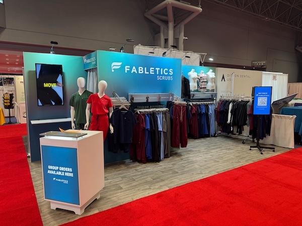 An exhibit for Fabletics Scrubs made by Cardinal Expo, featuring products on display as part of their interactive conference booth ideas.