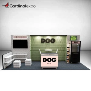 Front perspective of a 10x20 trade show booth featuring a green brick backwall, branded reception desk, television display, side shelving, and a custom claw machine game.