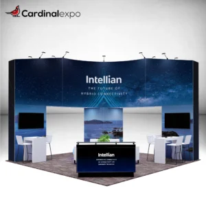 Front-left angle of a 20x20 trade show booth rental featuring a 3D backlit logo sign on a curved header wall, backlit reception desk, twin TV displays, and high-top seating stations.