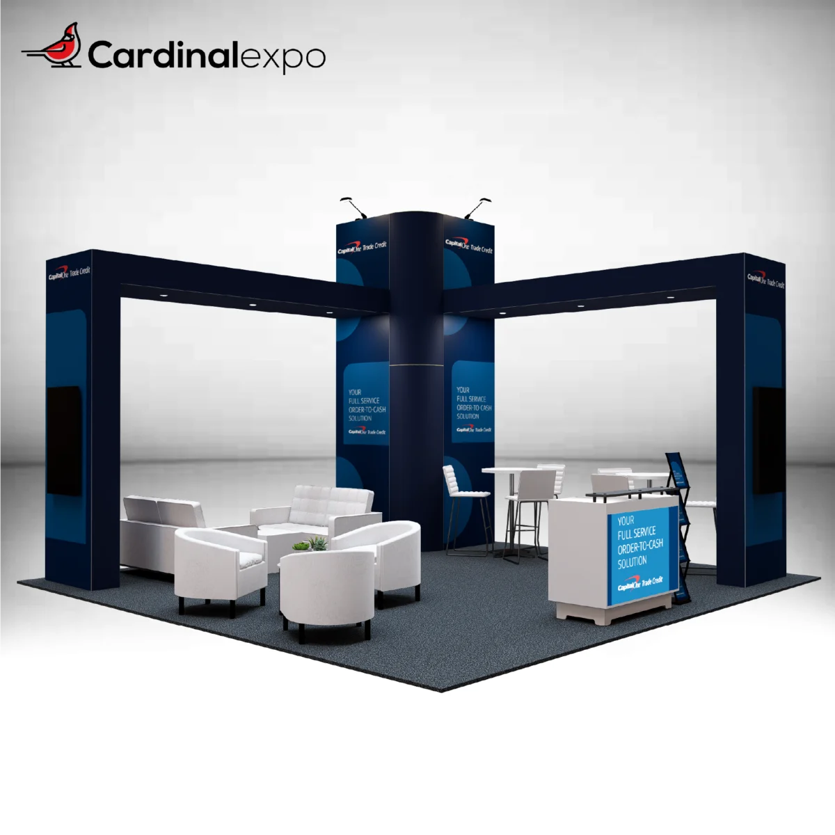 Front-left angle of a 20x20 trade show booth featuring a central graphic tower, dual structural arches, lounge furniture, and reception desk.