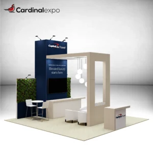 Front-left angle of a 20x20 trade show display rental showcasing a tall blue tower with a 3D backlit logo sign, wood canopy lounge, living green wall accents, TV monitor, and reception desk with a 3D logo sign.