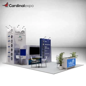Front-left perspective of a large custom trade show booth rental highlighting a reception counter, bistro meeting sets, TV display wall, and tall tower structure.